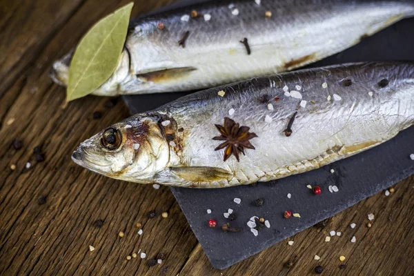 Dos peces. El arenque en las especias sobre la mesa de madera, al pez picante —  Fotos de Stock