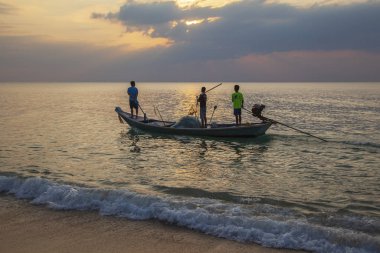 Vietnamlı balıkçılar gün batımında denizde bir balıkçı teknesinde