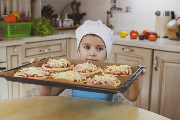 Маленький мальчик помогает маме готовить пиццу. Счастливая мама семьи и — стоковое фото