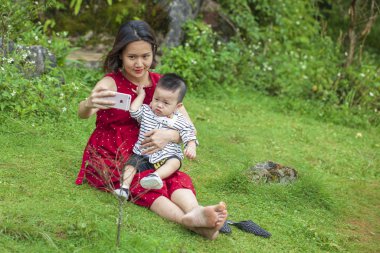 Genç anne oğluyla Gras 'da parkta selfie çekiyor.