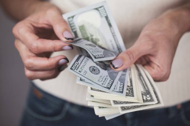 Döviz kuru, elinde para olan mutlu bir kız, dolarları sayıyor, yakın plan, kadın eli bize dolar banknotları sayıyor. 