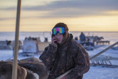  Far North, Yamal Peninsula, Reindeer Herder's Day, local residents in national clothes of Nenets, Hunter, man in ski glasses in camouflage clothing clipart