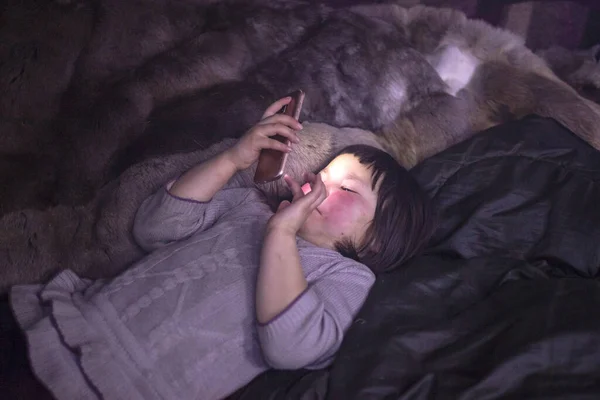 Far north, tundra, girl-assistant to reindeer herders with a phone in their hands in a yurt