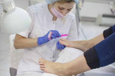 Güzellik salonundaki pedikür uzmanı tarafından yakın plan tırnak bakımı. Pedikür, pedikür için şeffaf tırnak makası..