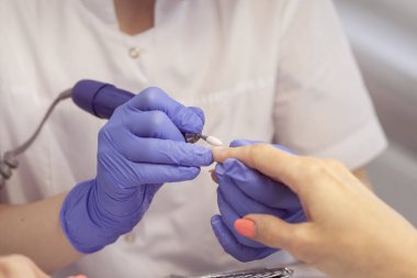 Profesyonel manikür. Elektrikli tırnakları olan bir kızın tırnaklarını ojelemek..