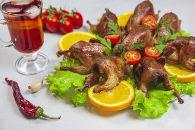 Turuncu üzerine kızarmış bıldırcın leşi, domatesli ve taze maydanozlu gri arka planda.