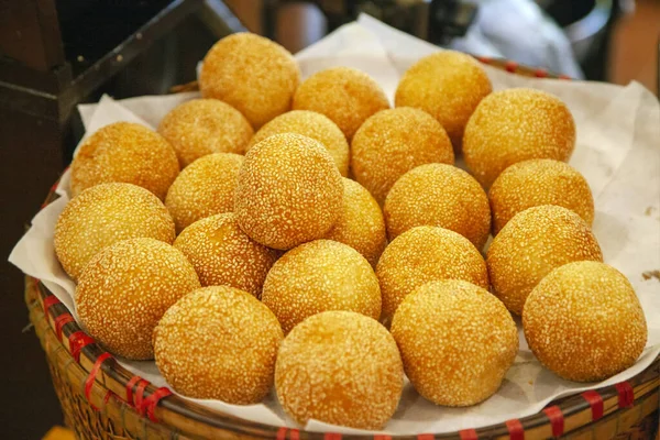 Traditional Vietnamese sweets. Cooking round donuts with sesame seeds, fried in a pan with butter