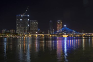 Danang, Vietnam, 30 Haziran 2019: Aydınlatılmış gökdelenler ve Han Nehri köprüsü Gece Da Nang, Vietnam 