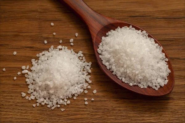 Sea salt, large, spoon with sea salt on a natural wooden background