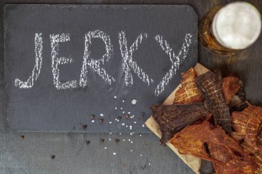 Biftek, tavuk ve hindi eti siyah arka planda bir tabakta, tebeşirle yazılmış kurutulmuş et, yukarıdan görünüm