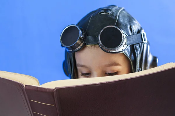 April 23, World Book Day, Concept - reading and enlightenment - the path to knowledge, a boy in a pilot helmet reads a book