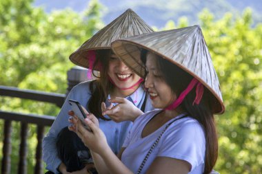 Ninh Binh, Vietnam- 22 Haziran 2019: Vietnamlı kızlar telefonla fotoğraf izliyorlar