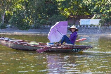 Ninh Binh, Vietnam, 21 Haziran 2019: Tam Coc Ulusal Parkı, Vietnamlı kadınlar bacakları tarafından kontrol edilen teknelerle turistlere biniyor.