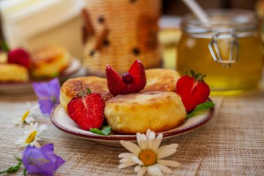 Kahvaltıda peynirli büyük bir tabak, süzme peynirli krep, taze çilekli krep ve papatya çiçekli çilek.