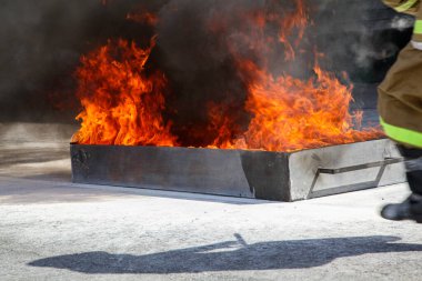 Büyük bir yangını söndürmek. Özel takım elbiseli profesyonel bir itfaiyeci yangın söndürücüyle yangını söndürüyor. İtfaiyecileri yangını söndürmek için eğitiyorum.