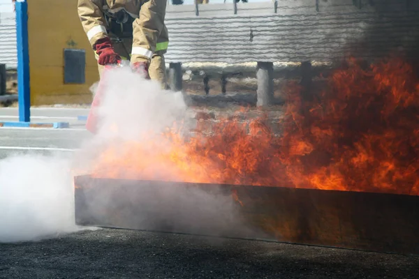 大きな火を消すんだ 特殊なスーツを着たプロの消防士が消火器で火災を消火します 消火訓練消防士 — ストック写真