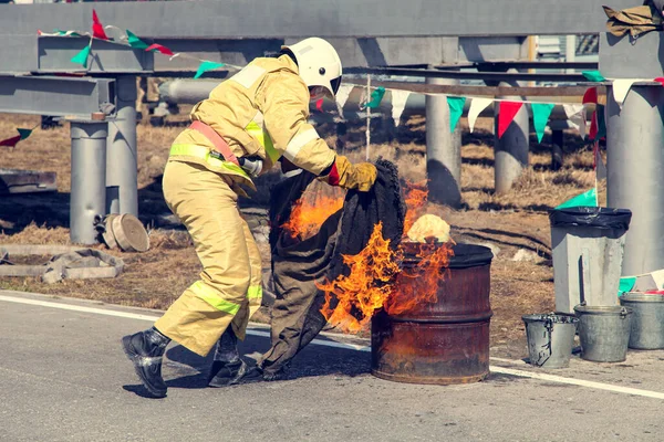 大きな火を消すんだ 特殊なスーツを着たプロの消防士が火事を消火します 都市部と契約消防士との訓練エリアでの地域消防演習 — ストック写真