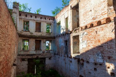 Eski bir tuğla binanın yıkıntıları, harabe duvarlar, boş pencereleri ve çatısı olmayan harabe bir kırmızı tuğla evin eski duvarı..