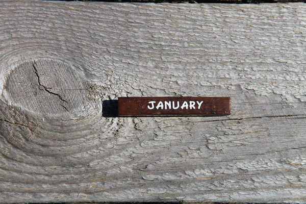 Wooden cube with the name of the month at the old board. January — Stock fotografie