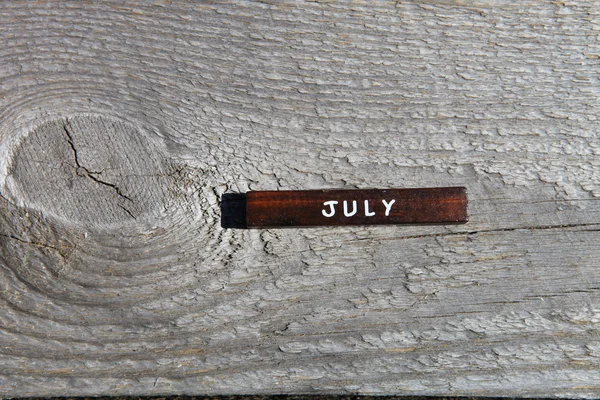 Wooden cube with the name of the month at the old board. July
