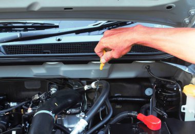 Adam arabanın içinde yağ kontrol seviye çubuğu kullanarak