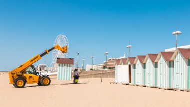 Dismantling beach huts at the end of the summer season clipart
