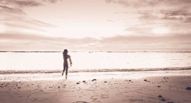 bir wetsuit giyinmiş kız sahilde çalışır