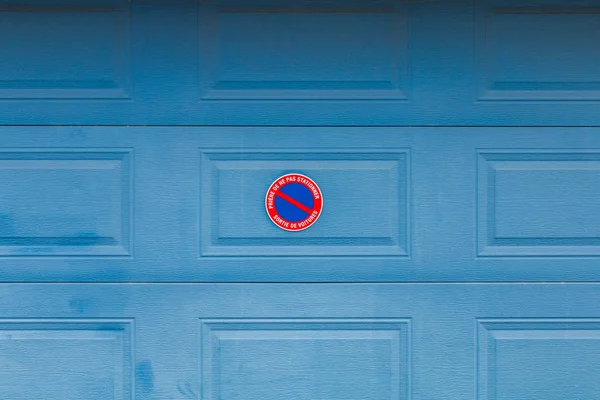 Puerta del garaje con panel en francés "Por favor no aparcar Salida del coche " — Foto de Stock