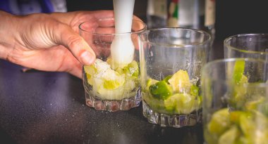 Barmen caipirihnas yapmak için bir hap ile yeşil limon ezen