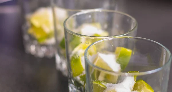 Limette in Gläser mit Zucker geschnitten, um Caipirinhas zu machen — Stockfoto