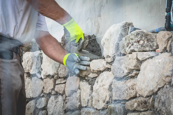 işçi taştan bir duvar bir geleneksel yenileme ücreti sürmek.
