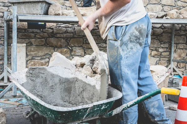 Homem faz concreto em um carrinho de mão em um local de renovação — Fotografia de Stock