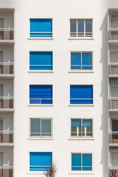 Fachada do edifício com janelas com persianas azuis — Fotografia de Stock