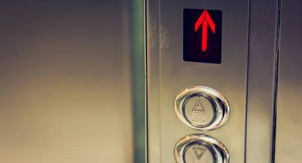 elevator button up and down and a screen that shows a red arrow