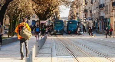 yoldan geçenler tarafından bir şehirde sokak arasında çalışan bir tramvay görünümünü