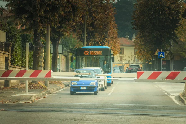 Coches y un autobús esperando detrás de las puertas de un cruce de ferrocarril — Foto de Stock