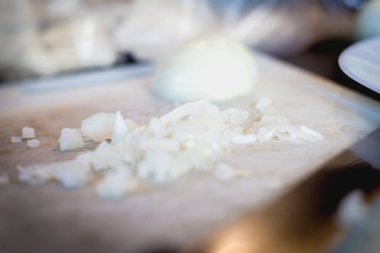 Kadın beyaz plastik bir tahtanın üzerinde soğan kesiyor. 