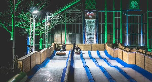 Enfants et adultes luge sur une glissière de glace installée à la — Photo