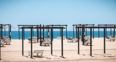 Tavira Adası, Portekiz - 3 Mayıs 2018: Bir bahar günü güzel kumlu kumsalda depolanan şezlonglar ve şemsiyeler