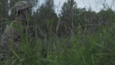 Askerler çimenlerde bekliyor. Tepenin üzerinde silah ordu