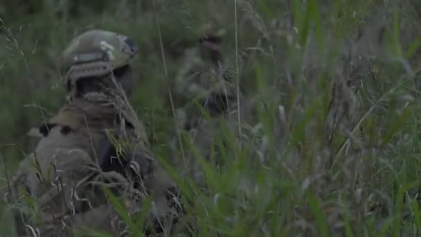 Soldiers sitting in wait in the grass. Military in arms over the hill — Stock Video