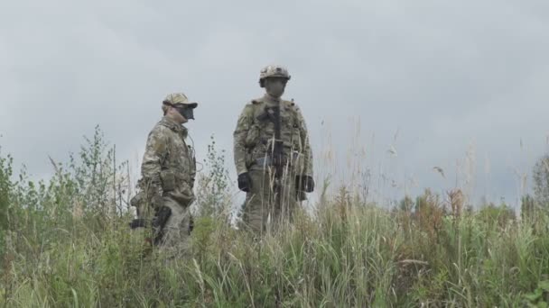 Dois militares em campo e falam com uma arma na mão. — Vídeo de Stock