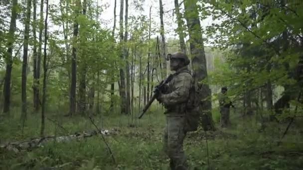 Soldiers go through the woods. Military with arms sent to the thickets of green. airsoft game — Stock Video