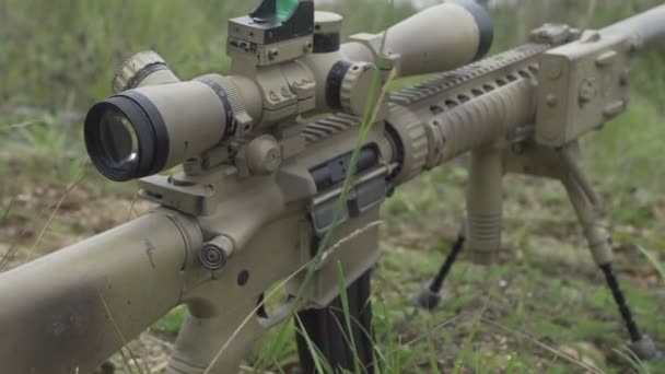 Kamouflage prickskyttegevär är på marken i gräset. Airsoft Guns — Stockvideo