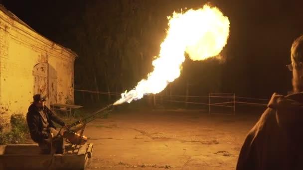 ผู้ชายยิงไฟจาก flamethrower บนสี่เหลี่ยมในตอนเย็น — วีดีโอสต็อก