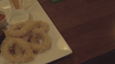 Soslu bir tabakta kalamar halkaları, kızarmış kanatlar, tost. Bira için snack