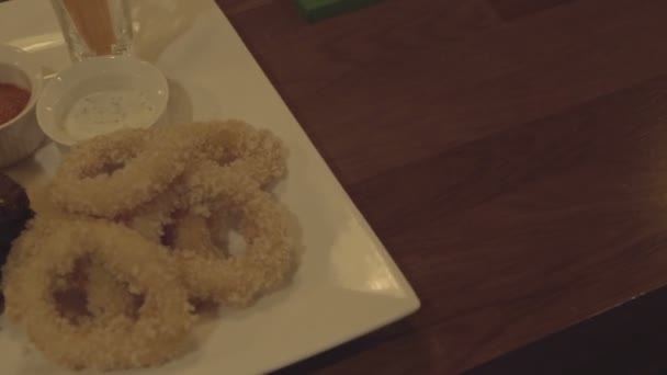 Кольца кальмара, жареные крылья, тосты на тарелке с соусом. Закуска к пиву — стоковое видео