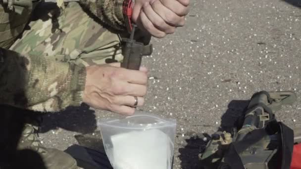 Чоловік у військовій формі заряджає кульки в клітці, резервуар авіаційної машини — стокове відео