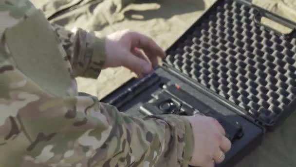 The soldier pulls a gun out of the case and insert the pistol with ammunition clip — Stock video