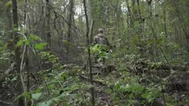 Soldat mit Waffe in der Hand geht durch den Wald — Stockvideo